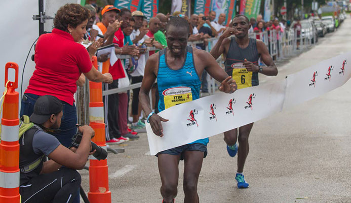 KENYAN PRIDE: Kenyan Stephen Mburi Njoroge crosses the line to win the Trinidad and Tobago International Marathon in a time of 2:23:04.3. His brother Simon(background) came in second with a time of 2:23:05.