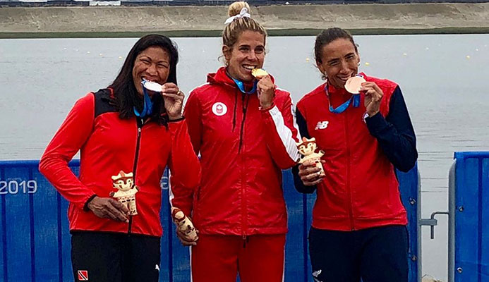 T&T's rower silver medallist Felice Aisha Chow, left, gold medallist Jessica Sevick of Canada, centre, and Chile's Soraya Jadue, the bronze medallist, bite down on their medals after the presentation ceremony for the women's singles sculls at the Pan American Games in Lima Peru on Friday.